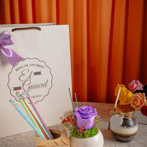 -Bolsa de regalo -Portalápices con rosa preservada en maceta de cerámica -Postre artesanal -Tarjeta con mensaje y de/para